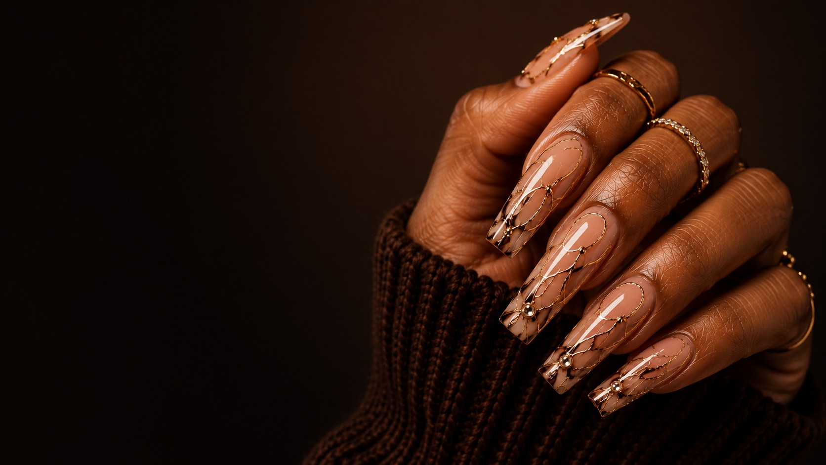 Elegant manicured nails with gold detail on rich brown skin